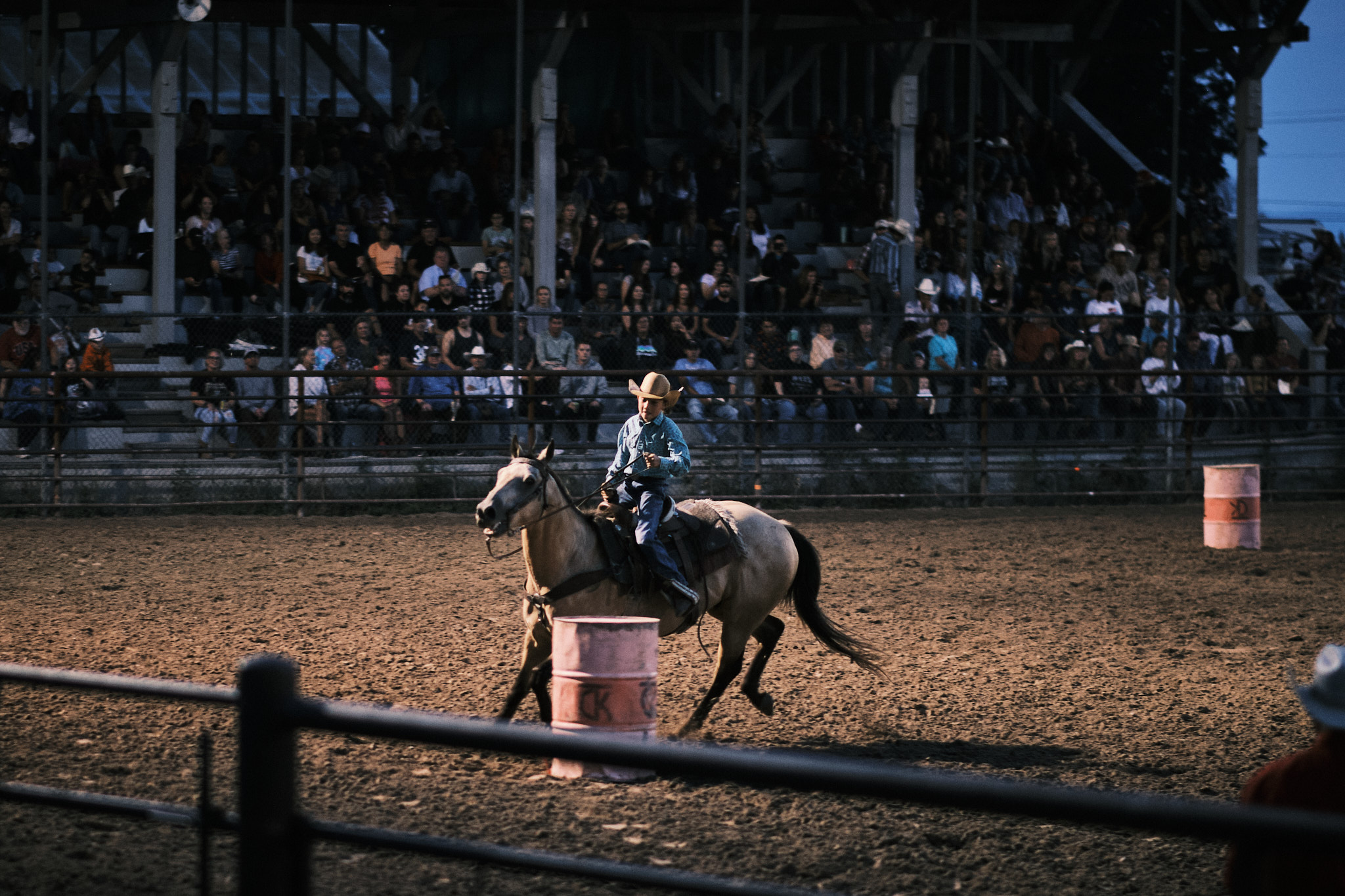 A young cowboy barrel racing his horse around a barrel