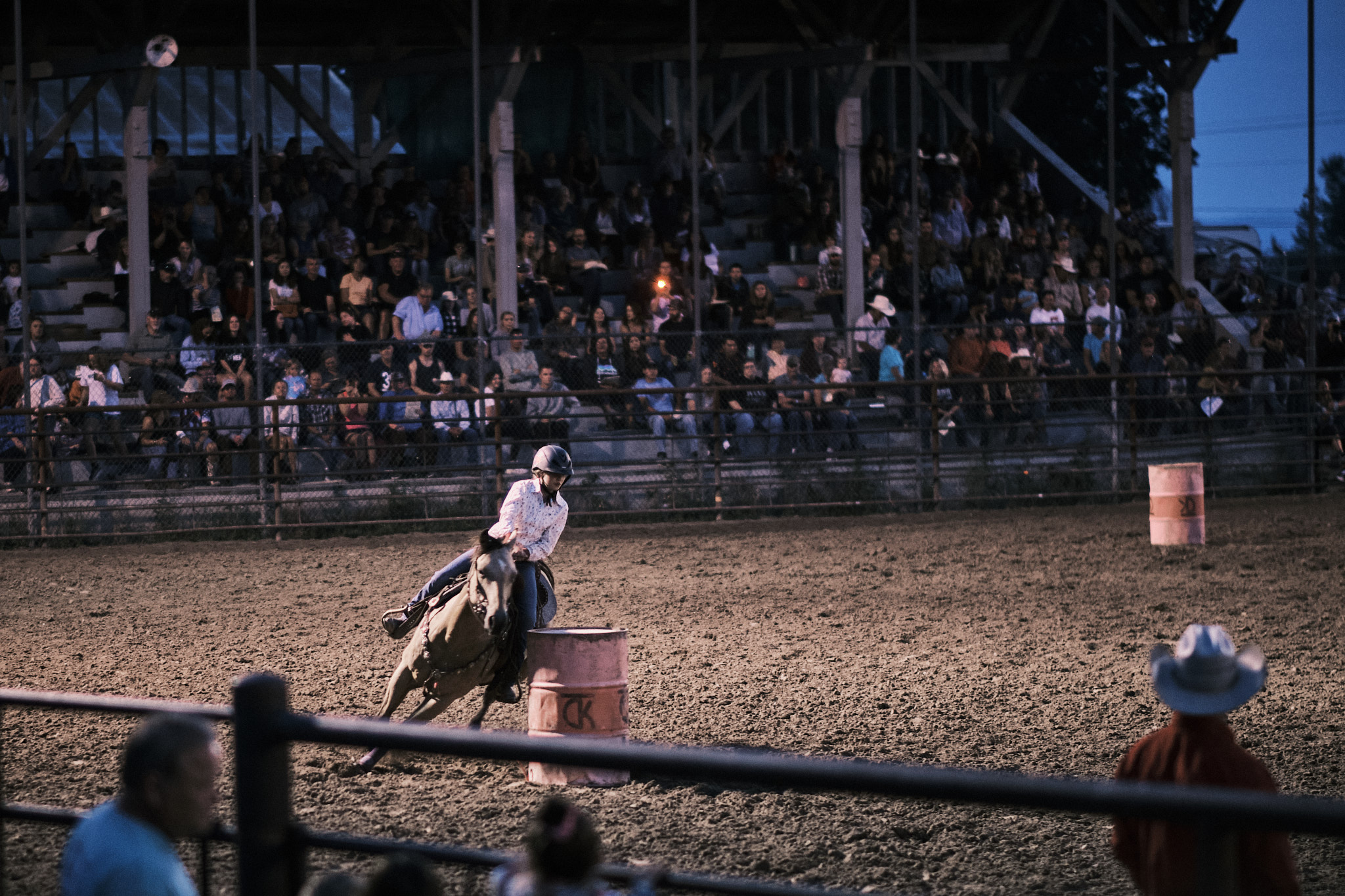 A young cowgirl barrel racing her horse around a barrel